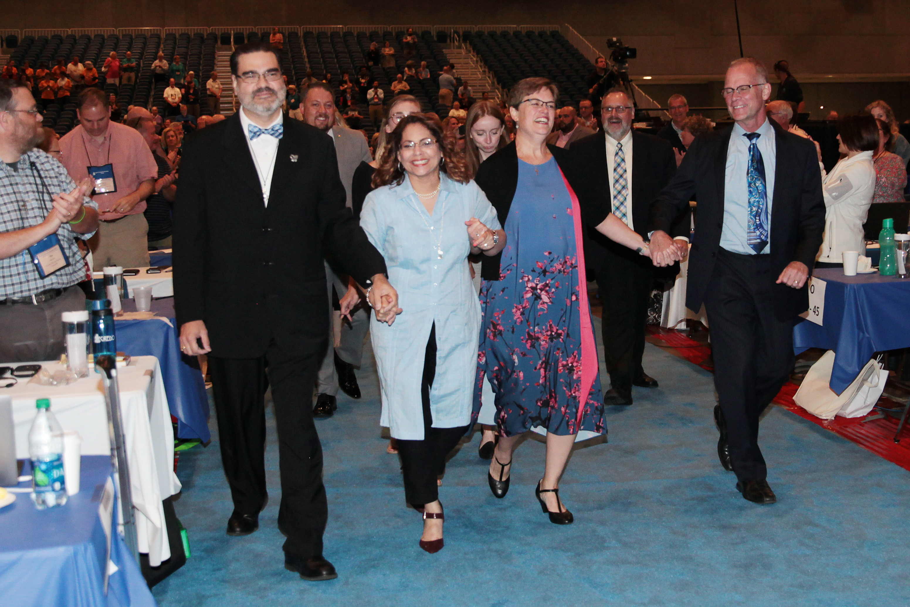 Vilmarie Cintrón-Olivieri (center-left) and Cindy Kohlmann (center-right) enter the plenary hall after their election as co-moderators. Photo by Danny Bolin.