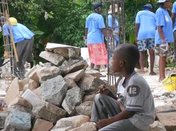 A young boy watches a Haitian work crew clear rubble 