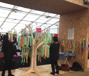 Participants write the place of the earth they love—and would hate to lose to climate change—on ribbons to hang on this Climate Ribbon Project tree.