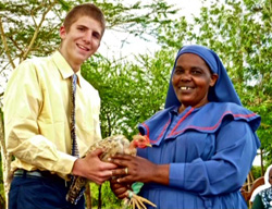 A young man and a woman in traditional Kenyan dress holding a chicken.