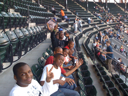 Boy in a row at baseball stadium waving.
