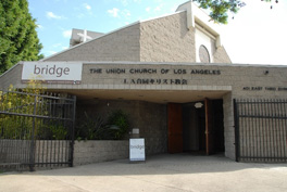 Front view of a granite church building with the words "The Union Church of Los Angeles" with Japanese text below it and a white banner with the word "Bridge" to the left.