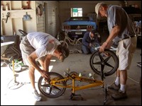 Two men repair a bicycle.