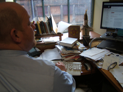 Charles Wiley, sitting at his desk with computer and files.