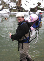 The Rev. Karlin Bilcher wearing fishing gear while standing in  water.