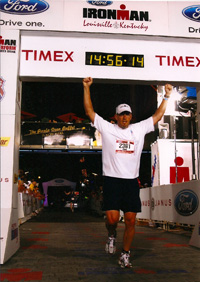 A man running, arriving under a white banner at the end of a marathon.