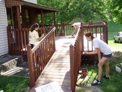 Carpenters work on a ramp leading to a porch.
