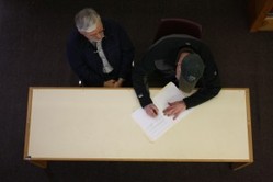 John Holst (left) and  Bob Banghart sign a document giving the former college's archives to the State Division of Libraries, Archives and Museums.