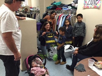 A clothes closet volunteer at Calvary Presbyterian Church in Riverside, California offers a Batman shirt to a young boy.