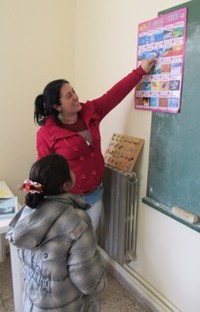 A Syrian girl reads a chart of English and Arabic words after her first month of attending school.