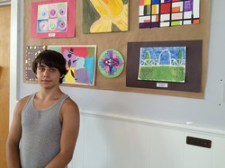 Chris Omelchuk standing in front of art he created at Beacon’s after-school program.