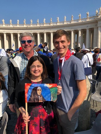노마 티만은 그녀의 조상인 마리아 카타리나 카스퍼의 사진을 바티칸 성베드로 광장에서 남편 Bob(왼쪽)과 Kevin Herrmann(오른쪽) 및 독일 교구와 함께 들고 있다.
