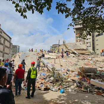 The image shows earthquake destruction in Venezuela, including destroyed buildings and roads. Volunteers and first responders are shown removing debris.