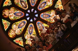 Photo of a congregation seated in front of a colorful stained glass window
