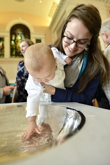 At Central Presbyterian Church in Louisville, Molly Atkinson holds her 10-month-old niece, Nora, as she touches her baptismal water.