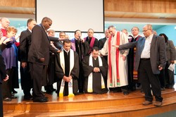 Amgad Megally (left) and Amir Tawadrous (right) kneel as elders and community members lay hands on them during their ordination service.