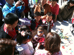 A group of children and adults, gathered together with coloring supplies and a large paper.