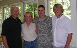 A small group of family members standing with a solder in his fatigues.