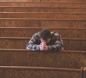 man praying in church pew