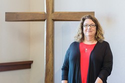 Woman minister standing next to cross