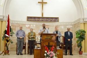 Elmarie and Scott Parker (left and right of podium) and Amgad Beblawi (far right) worship together in Bagdad.