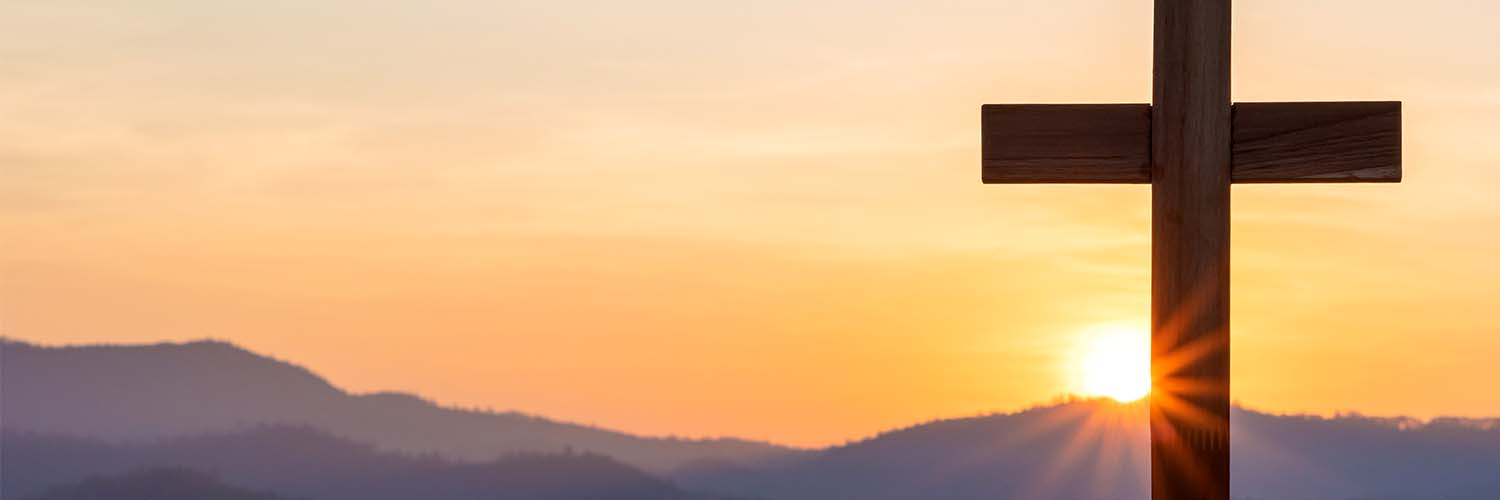 Cross on top of hill with sunlight illuminating from behind. By AungMyo - Adobe Stock