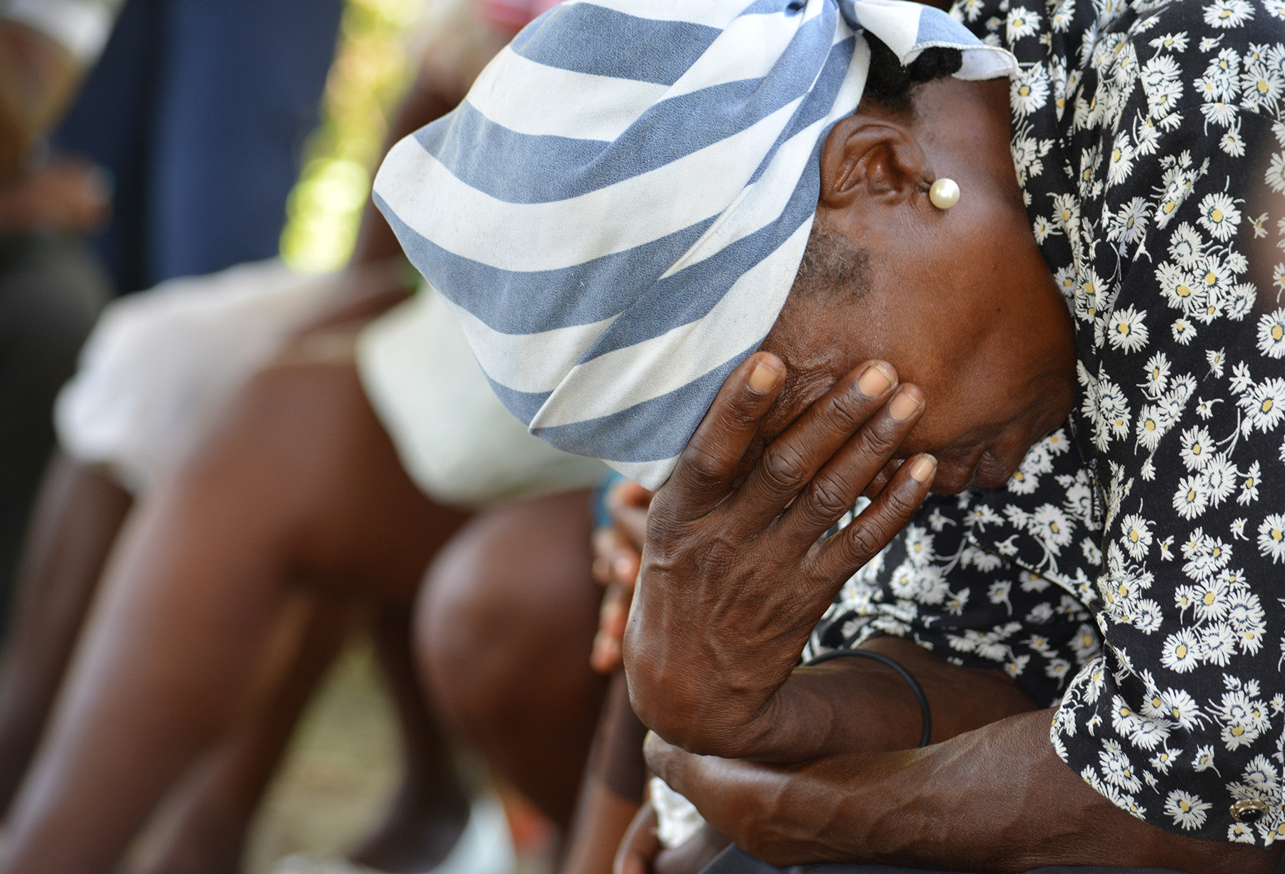 Image of woman in Haiti with her head cradled in her hands. Image courtesy of Cindy Correll 