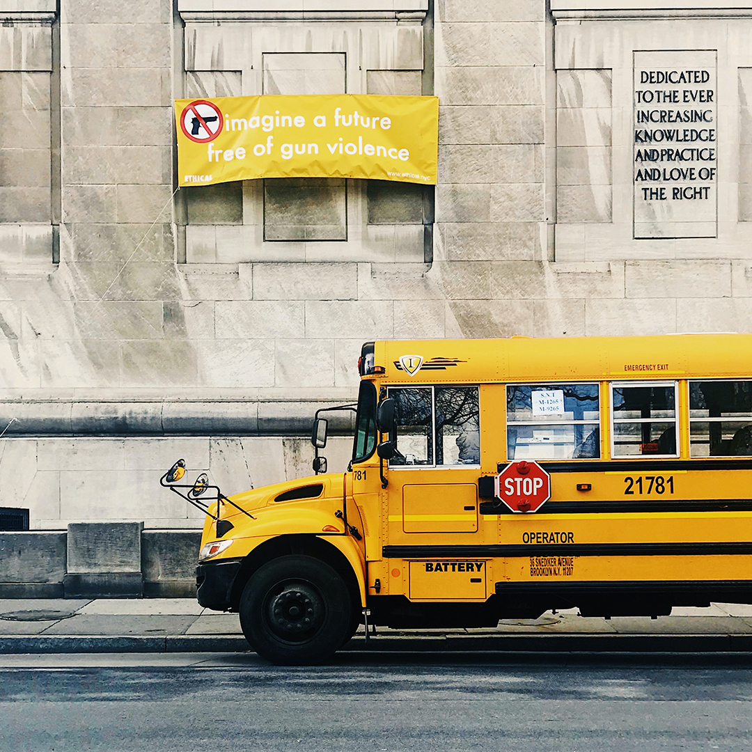 Photo of school bus in front of school, with banner saying Imagine a Future Free of Gun Violence. Photo by Jose Alonso via Unsplash 