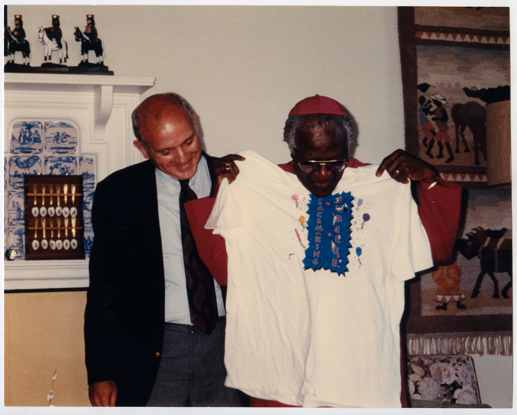 Archbishop Desmond Tutu (right) models a Peacemaking Jubilee t-shirt in his Cape Town residence. The Rev. Ken Jones (left) of Cleveland makes the presentation on behalf of 20 U.S. Presbyterian participants in the November 1994 Study/Travel Seminar to South Africa/Namibia, sponsored by PPP. From Pearl: 348265 [RG 542, Box 34, Folder 11]