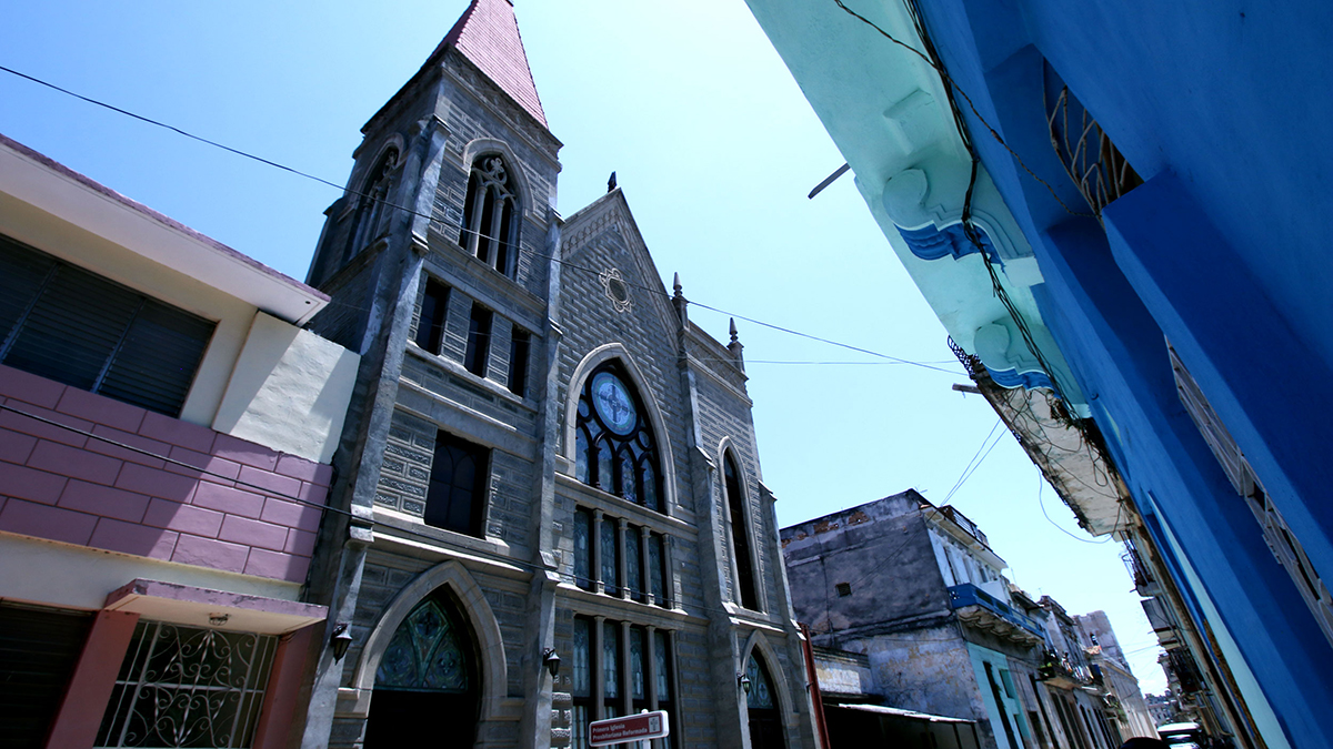 Primera Iglesia Presbiteriana Reformista towers over a bustling urban throughway in downtown Havana. 