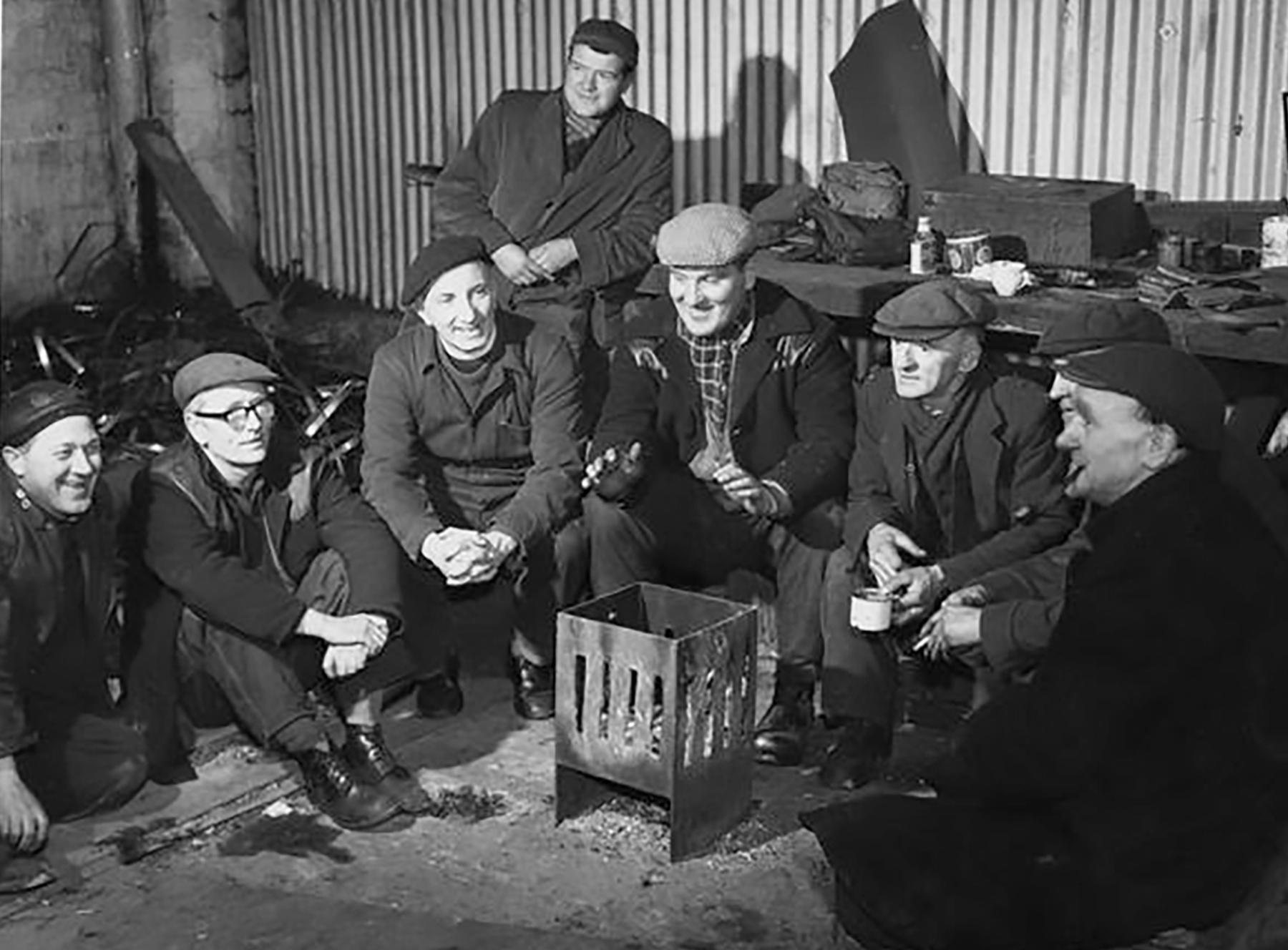 Shipyard workers at Port Glasgow, Scotland, are joined during their lunch break by the Rev. J. Cameron Wallace, a Church of Scotland chaplain, 1965. [Pearl ID: 151434]